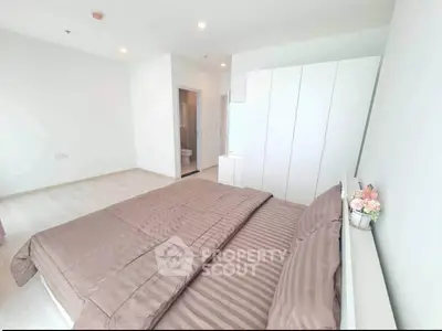 Spacious bedroom with modern decor and ample natural light, featuring a cozy bed and sleek wardrobe.