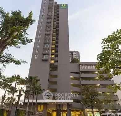 Modern high-rise building with lush greenery and elegant entrance.