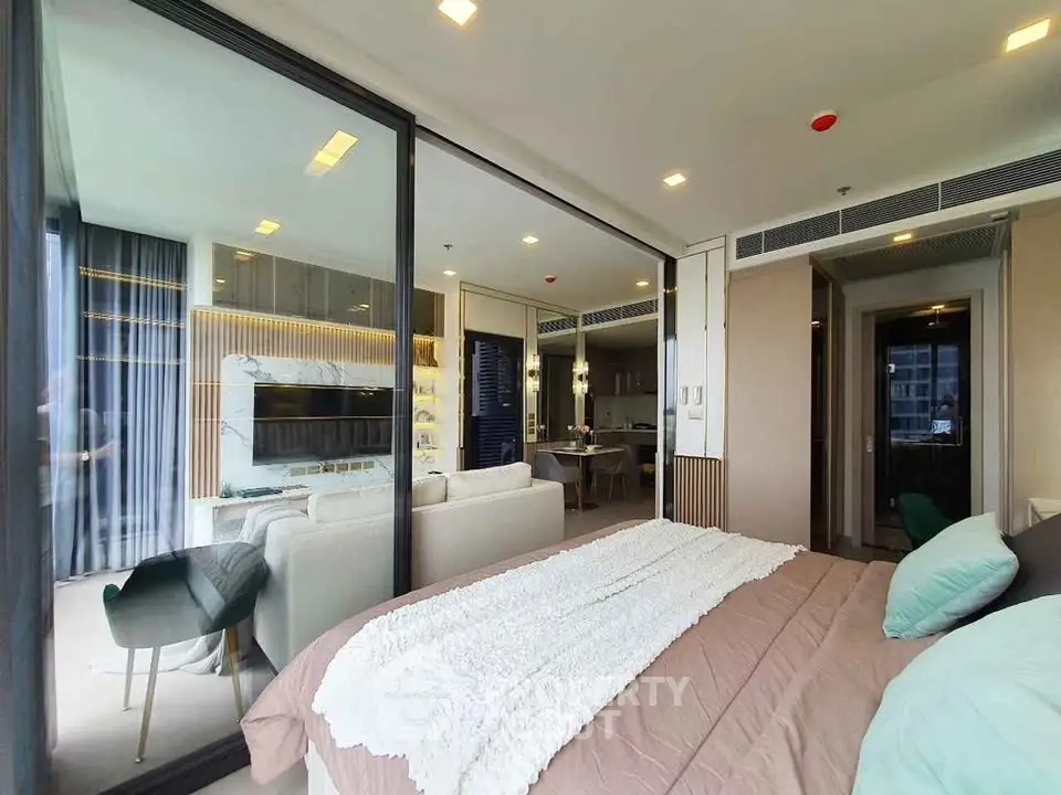 Luxurious modern apartment with open layout, featuring a cozy bedroom and stylish living area separated by glass doors.