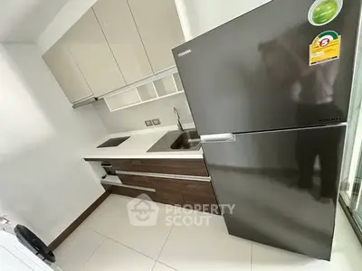 Modern kitchen with sleek cabinetry and stainless steel fridge in compact layout.