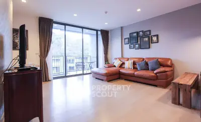 Spacious living room with leather sofa and large balcony access, perfect for modern living.