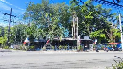 Charming roadside property with lush greenery and inviting outdoor seating area.