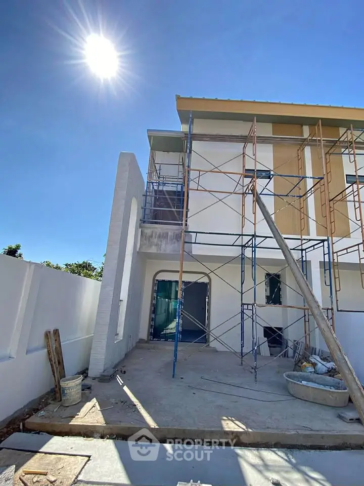 Modern house under construction with scaffolding and bright sunlight