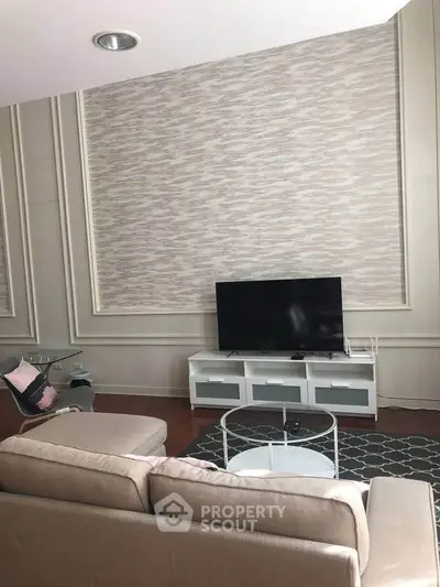 Elegant living room with modern decor, featuring a stylish sofa, flat-screen TV, and chic wall design.