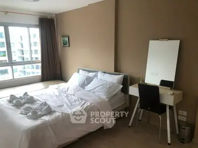 Spacious bedroom with modern decor and large window offering natural light.