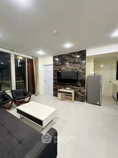 Modern living room with sleek design, featuring a wall-mounted TV and stylish furniture.