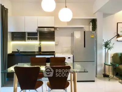 Modern kitchen with sleek appliances and dining area, featuring stylish lighting and contemporary design.