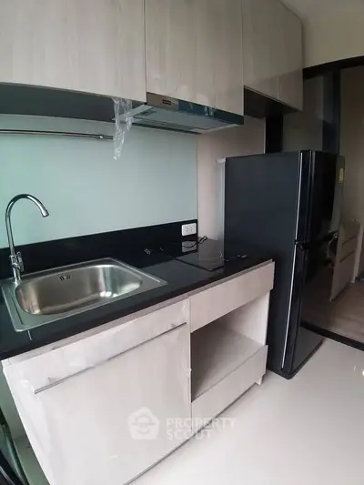Modern kitchen with sleek cabinetry and stainless steel sink in a compact layout.