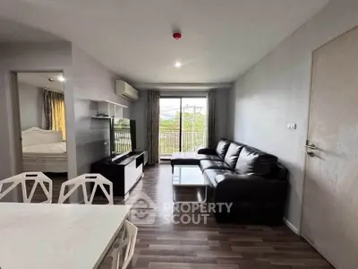 Modern living room with sleek black sofa, open layout, and natural light from large window.