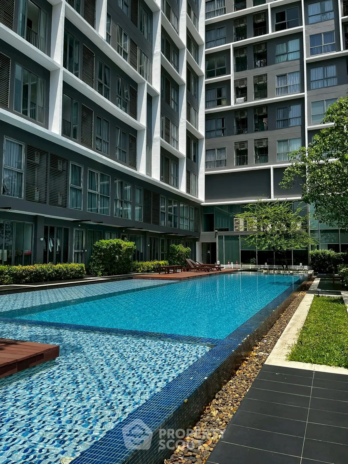 Modern apartment complex with luxurious swimming pool and lush greenery.