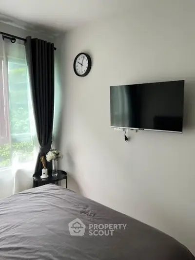 Modern bedroom with wall-mounted TV and large window for natural light.