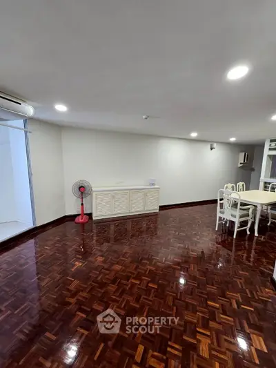 Spacious living room with polished wooden floors and elegant dining area.
