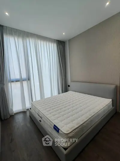 Modern bedroom with large window and stylish decor, featuring a comfortable bed and elegant curtains.