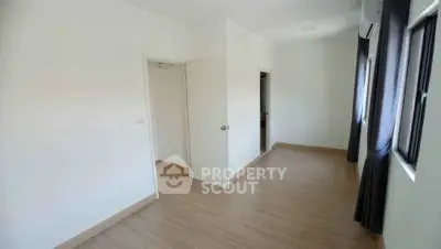 Spacious empty room with wooden flooring and large windows for natural light