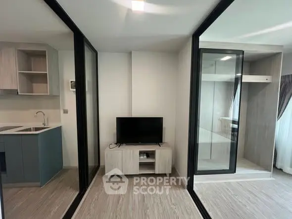 Modern apartment interior with sleek kitchen and cozy living area featuring a TV stand, ideal for urban living.