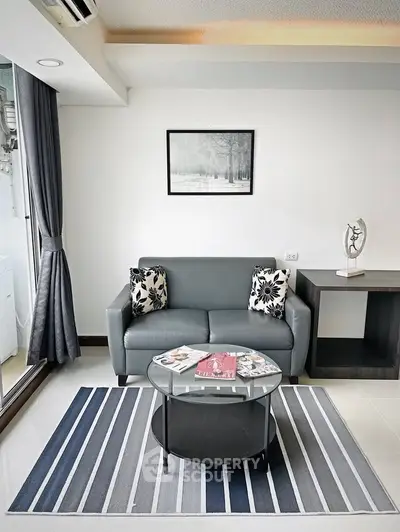 Modern living room with sleek sofa, stylish decor, and natural light from large window.
