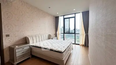 Spacious bedroom with elegant decor and large window offering city views