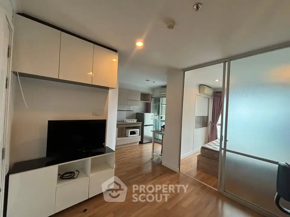 Modern open-plan living room with sleek kitchen and cozy bedroom in a stylish apartment.