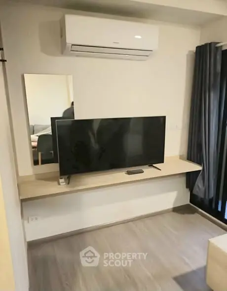 Modern living room with sleek TV setup and air conditioning unit.