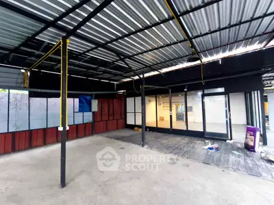Spacious covered outdoor area with metal roofing and glass doors, ideal for commercial use.