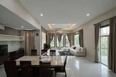 Spacious living room with elegant dining area and large windows offering garden views.