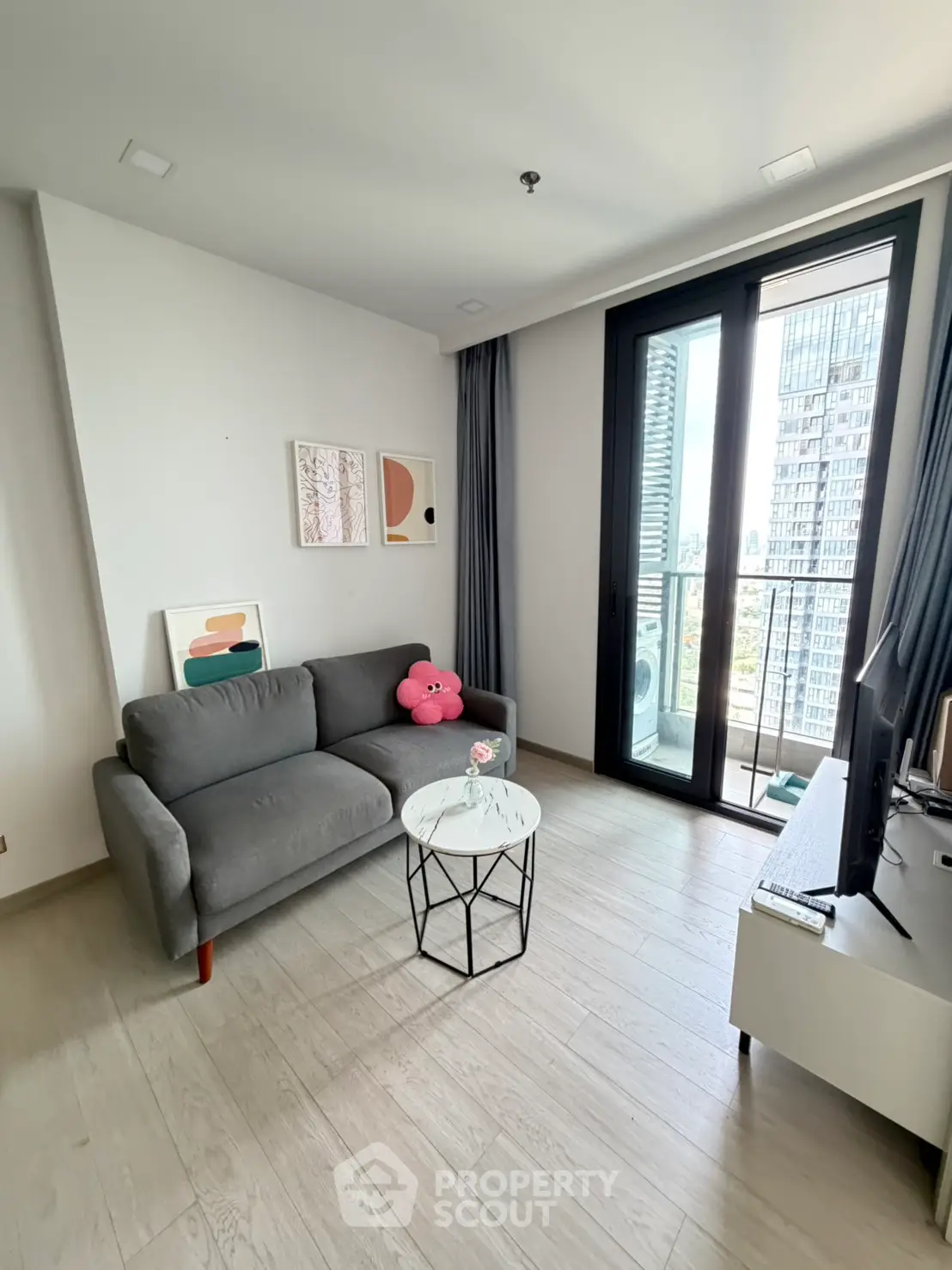 Modern living room with stylish decor and city view balcony in high-rise apartment.