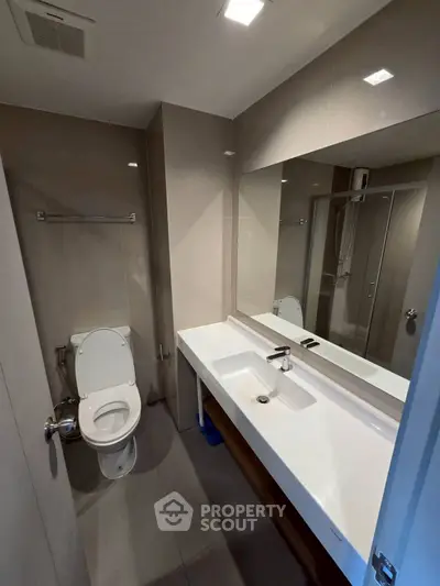 Modern bathroom with sleek fixtures and large mirror in a contemporary home.