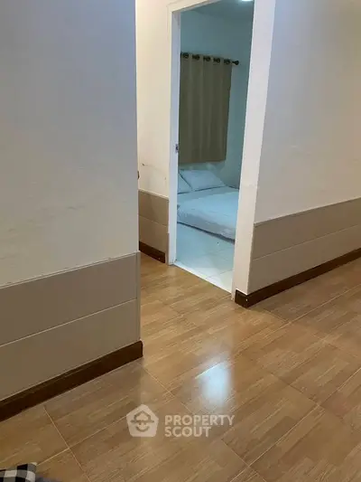 Cozy bedroom view from hallway with wooden flooring and neutral decor