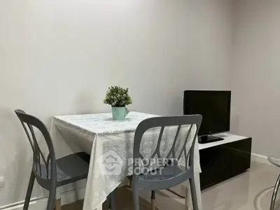 Cozy dining area with table, chairs, and TV in modern apartment.