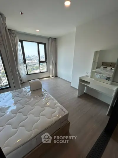 Modern bedroom with city view, featuring a comfortable bed and sleek vanity desk.