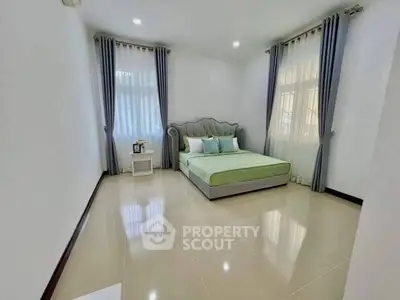 Spacious bedroom with elegant bed and natural light through large windows.