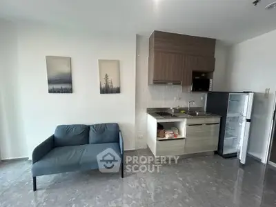 Modern open-layout kitchen with sleek cabinetry and cozy living area featuring a stylish sofa.