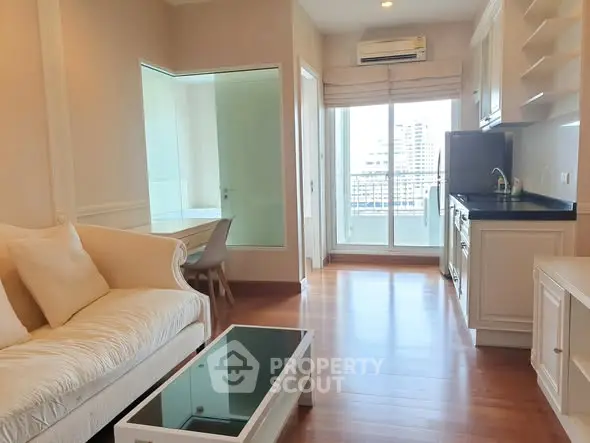 Modern living room with elegant sofa and glass coffee table, featuring a balcony view.