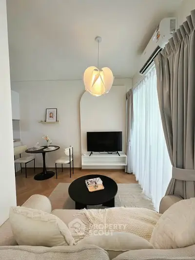 Modern living room with cozy sofa, stylish lighting, and natural light from large windows.