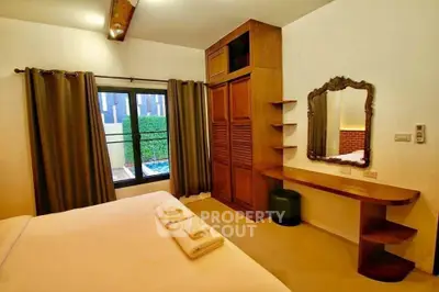 Charming bedroom with elegant wooden furniture and pool view, perfect for a cozy retreat.