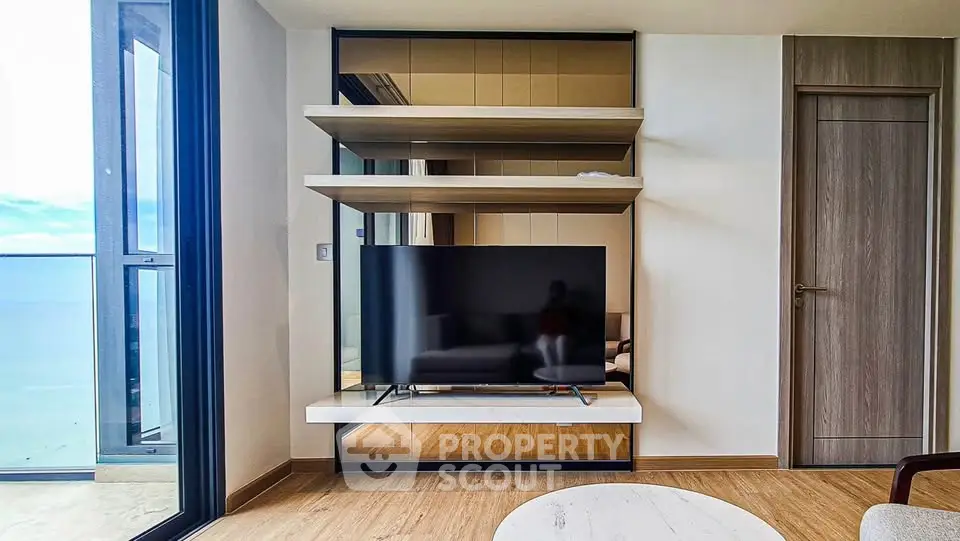 Modern living room with sleek TV setup and ocean view balcony
