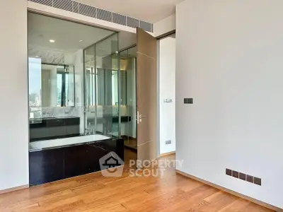 Luxurious modern bathroom with glass partition and elegant wooden flooring