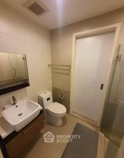 Modern bathroom with sleek fixtures and neutral tones, featuring a glass shower and contemporary vanity.