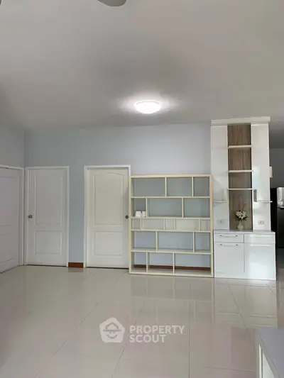 Spacious modern living room with sleek built-in shelving and bright tiled flooring.
