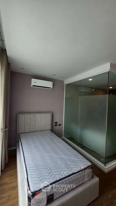 Modern bedroom with glass partition and air conditioning in a stylish apartment.