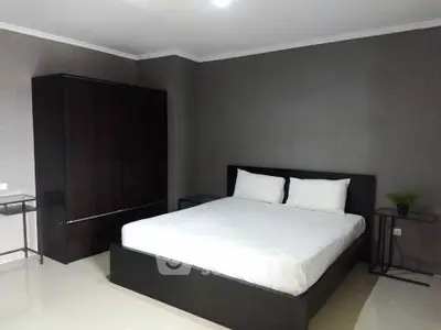 Modern minimalist bedroom with sleek dark furniture and neutral tones.