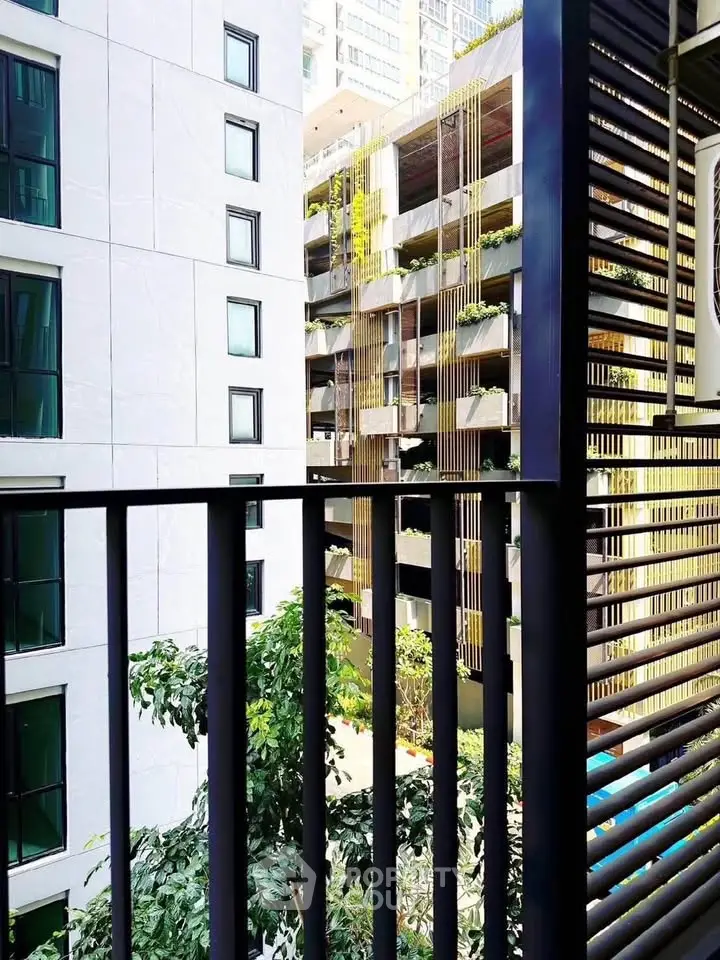 Modern urban view from balcony with lush greenery and contemporary architecture.