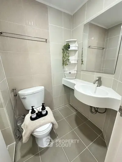 Modern bathroom with sleek fixtures and neutral tiles, featuring a unique corner sink design.