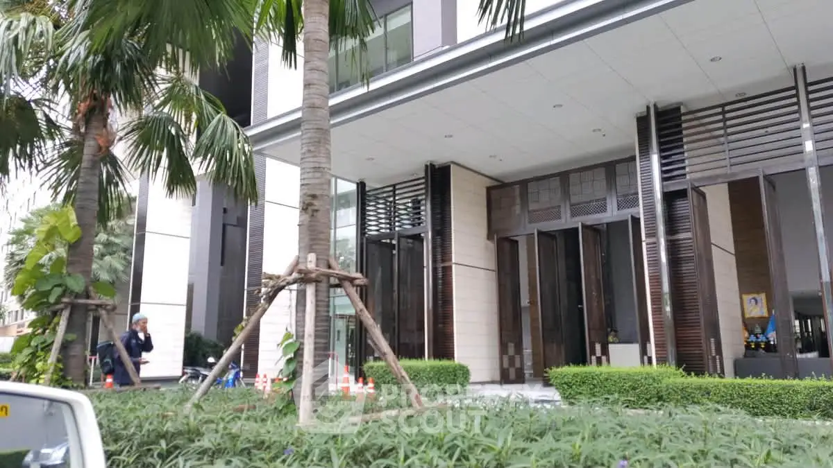 Modern building entrance with lush greenery and sleek architectural design
