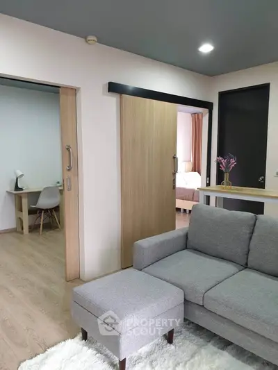 Modern living room with gray sofa, sliding doors, and cozy decor in a stylish apartment.