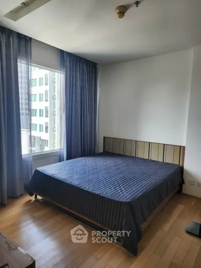 Spacious bedroom with large window and modern decor in urban apartment