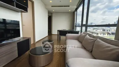 Modern living room with city view, featuring sleek furniture and large windows.
