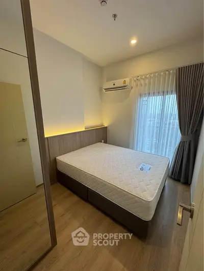 Modern bedroom with large window and minimalist design in a high-rise apartment.