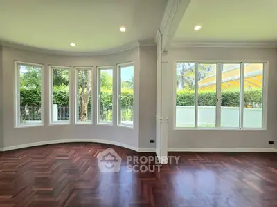 Spacious living room with large windows and elegant wooden flooring