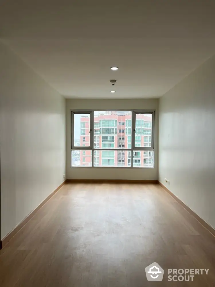 Spacious empty room with large window and city view, perfect for customization.